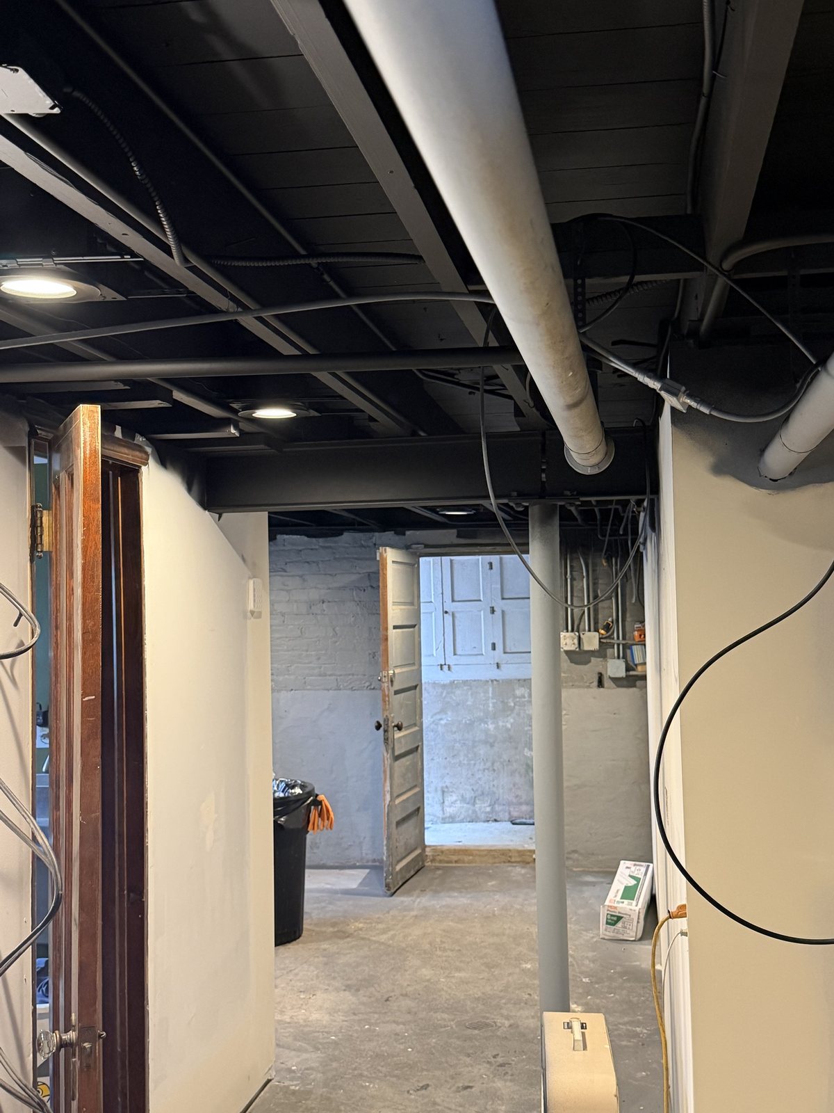 Basement with exposed ceiling sprayed flat black after painting